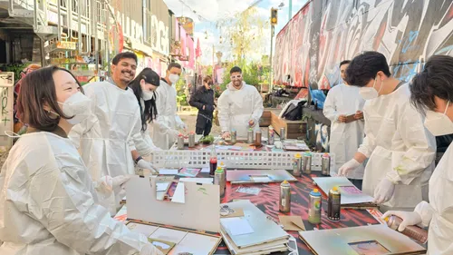 People in protective suits painting with spray paint outdoors.