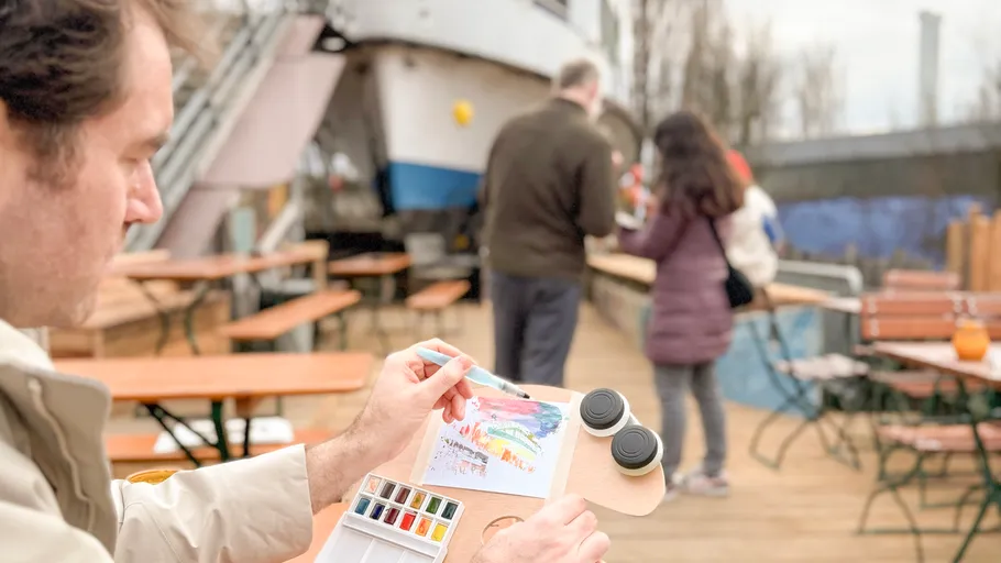 Man painting at outdoor café with tables.