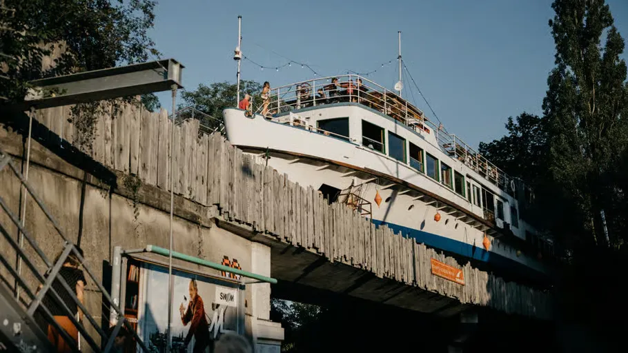 Boat on bridge with people, surrounded by trees.