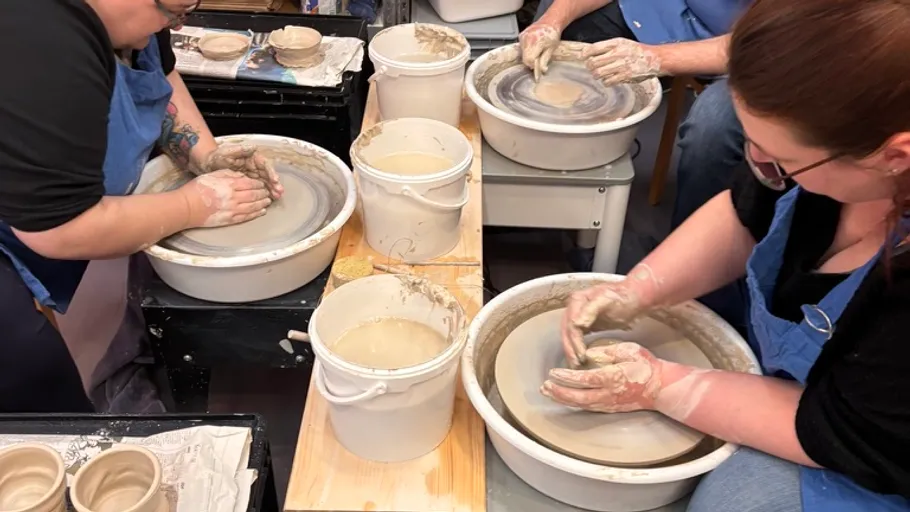 People molding clay on pottery wheels indoors.