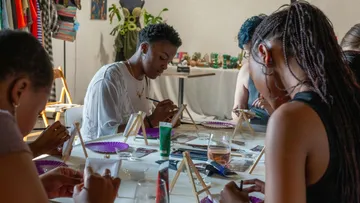 People painting at a table in a studio.