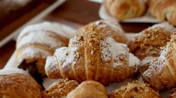 Croissants on a wooden table, sprinkled with sugar.