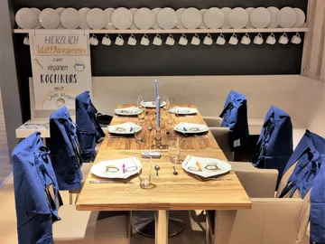Ein gedeckter Tisch für einen Kochkurs mit blauen Schürzen.