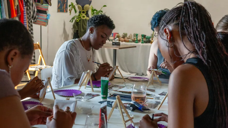 People painting at a table in a workshop.