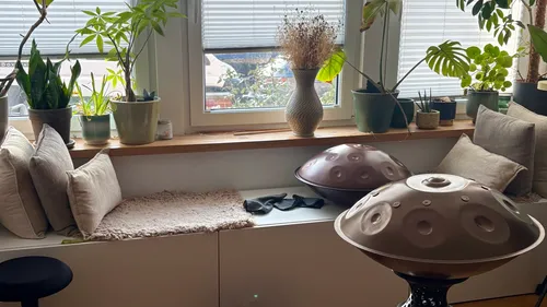 Handpans auf einer Bank mit Pflanzen und Kissen.