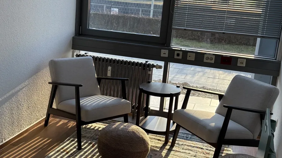 Zwei Stühle um einen kleinen Tisch am Fenster.