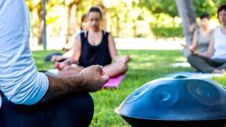 Menschen meditieren im Park mit einem Handpan.