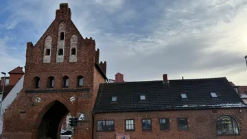 Historisches Backsteintorhaus unter wolkigem Himmel.