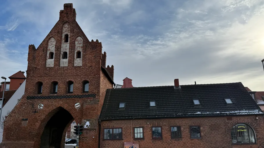 Historic brick gatehouse under cloudy sky.