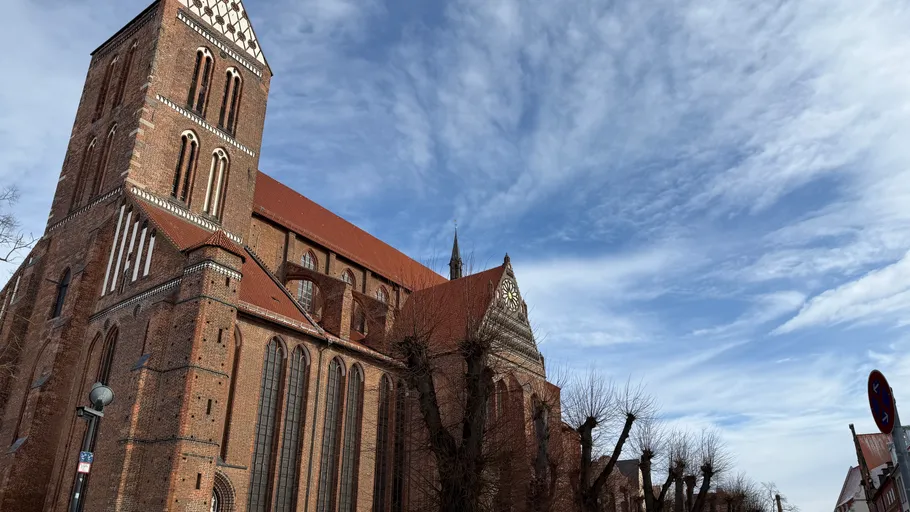 Brick church with red roof under blue sky.