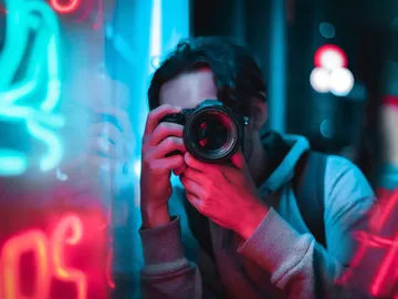 Ein Fotograf hält eine Kamera und nimmt Bilder auf.