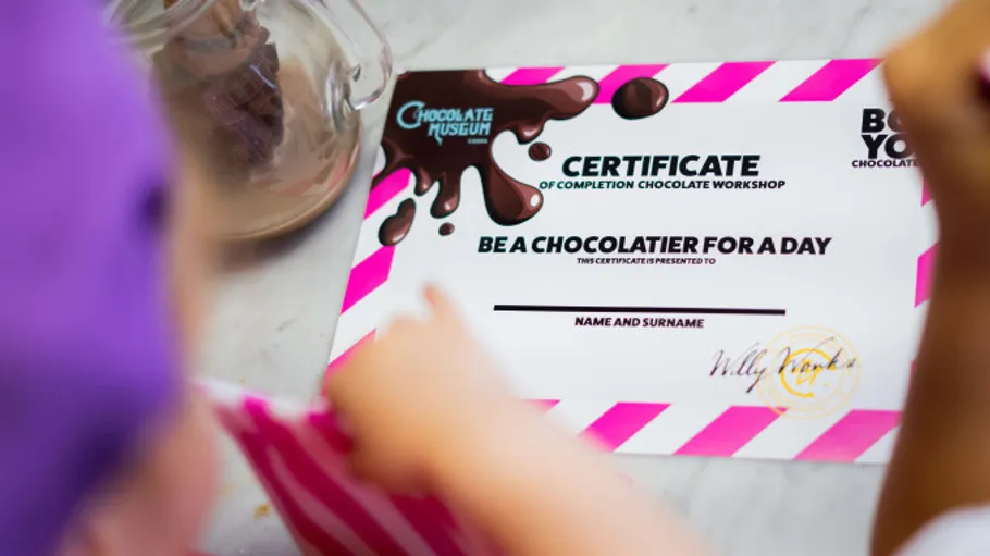 Child points at chocolater certificate on table.