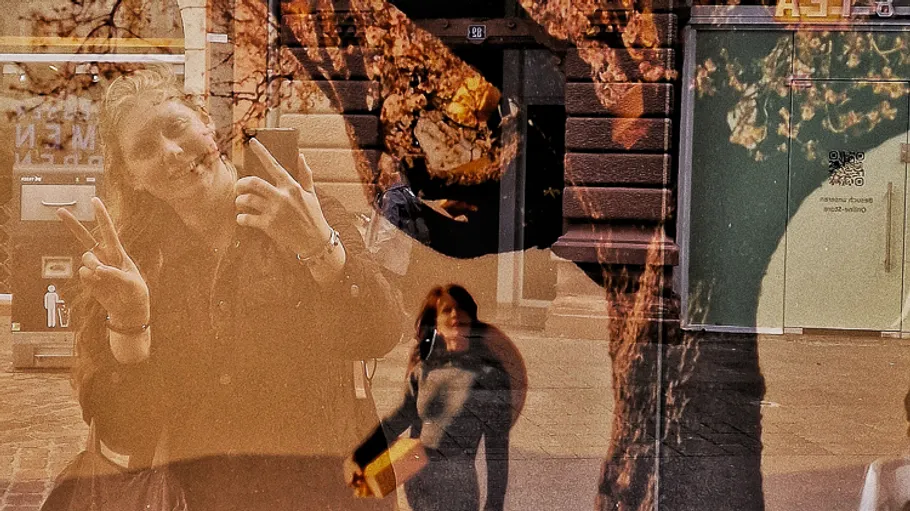 Reflection in glass with tree and people.