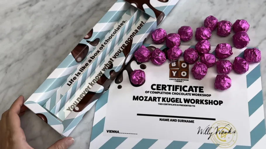 Certificate surrounded by foil-wrapped chocolates on table.