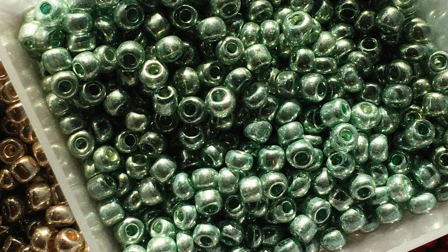 Green beads piled in a container.