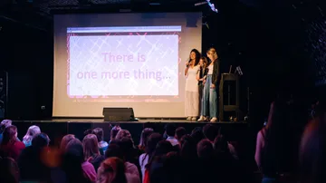 Three people presenting on stage to audience.