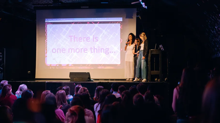 Three people presenting on stage to audience.