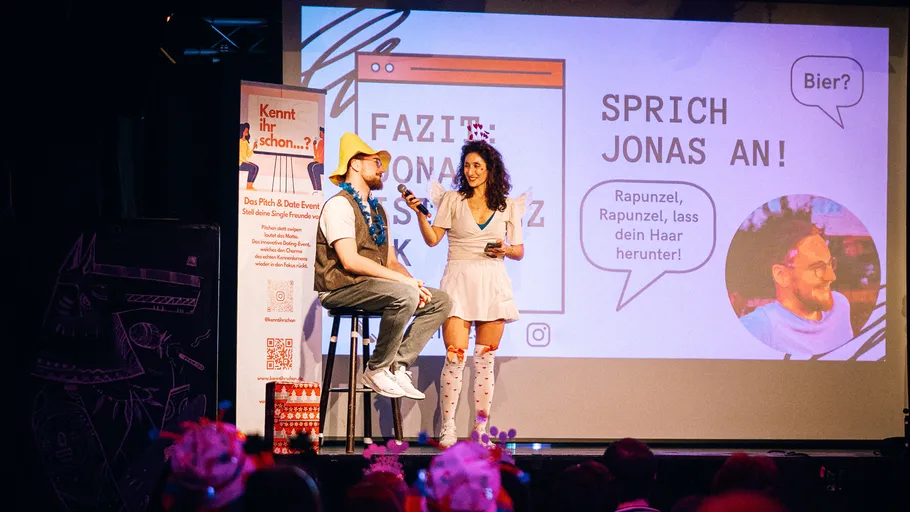 Zwei Personen auf einer Bühne bei einem Event.