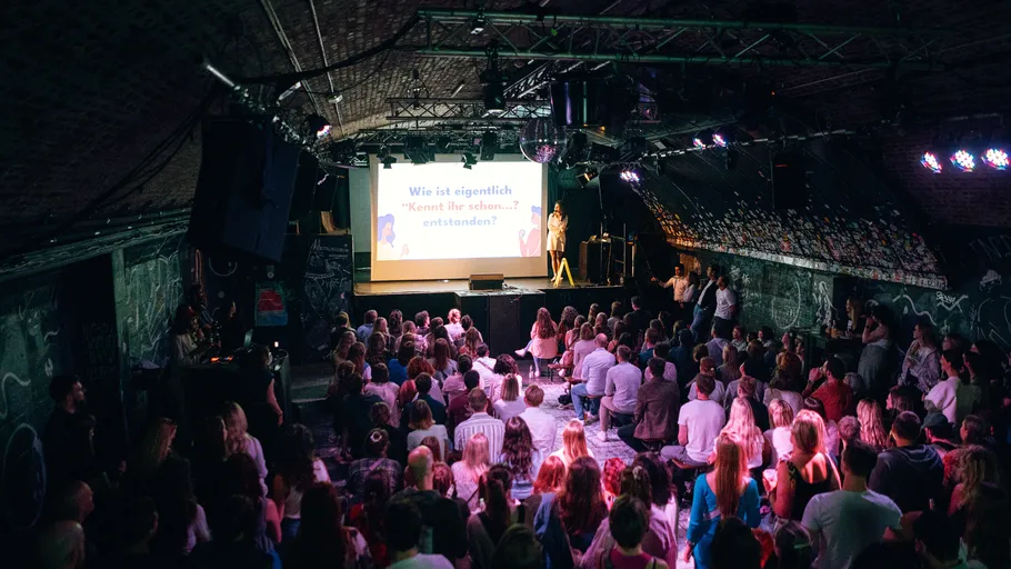 Audience watching presentation in dimly lit room.