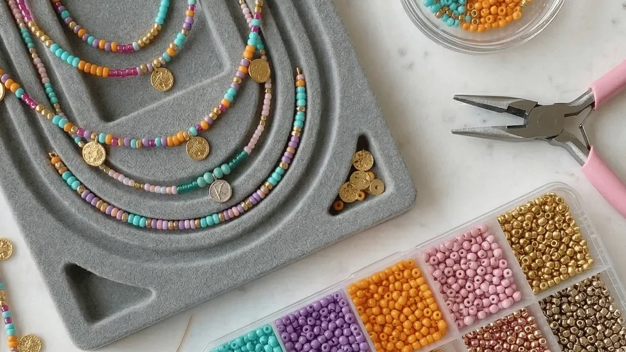 Colorful beads with pliers on crafting board.