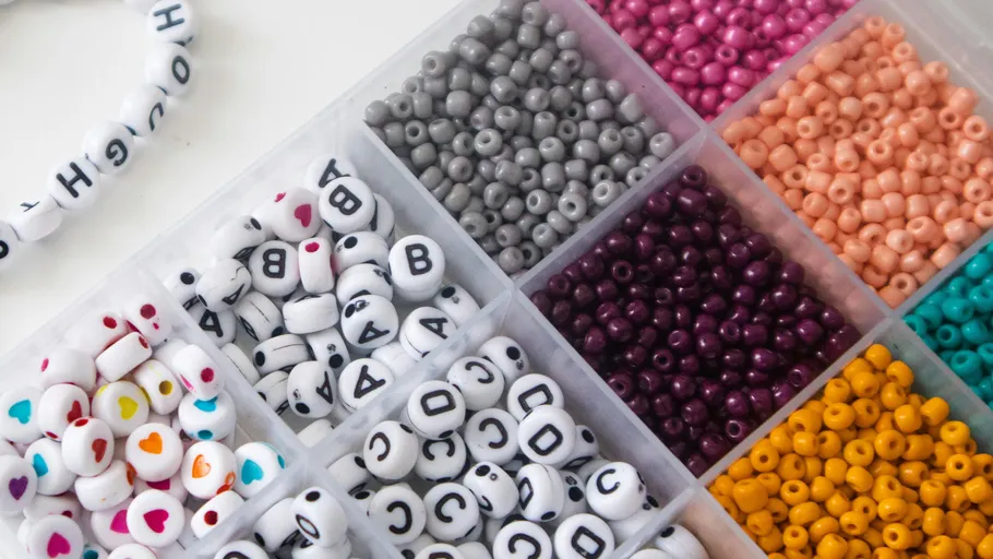 Colored beads organized in plastic container.
