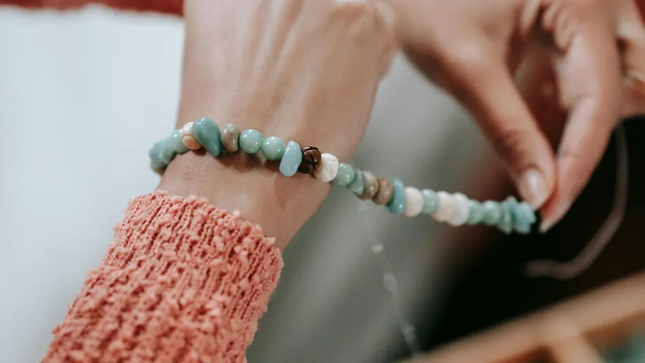 Person threading beads onto a string.