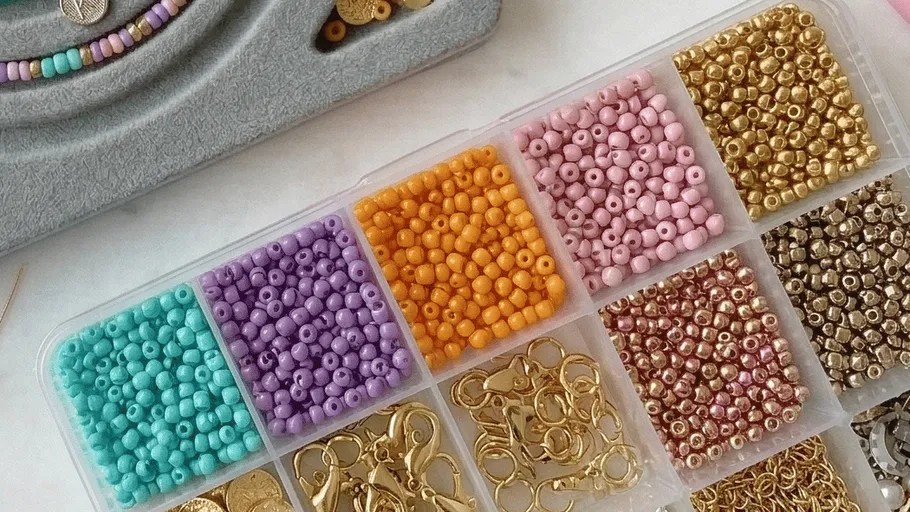 Colored beads and jewelry clasps in storage box.