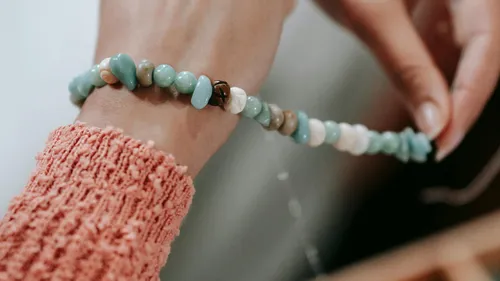 Hand fertigt ein Perlenarmband aus der Nähe.