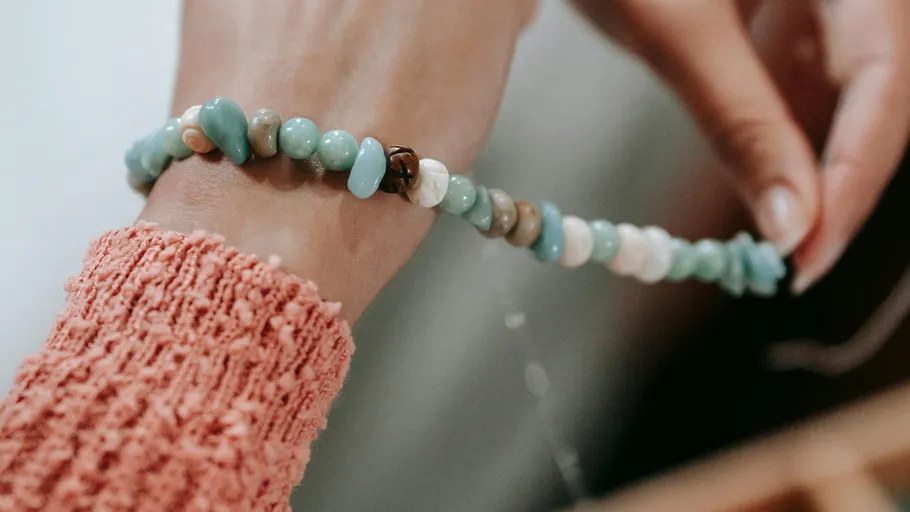 Hand fertigt ein Perlenarmband aus der Nähe.
