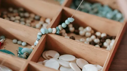 Beads being strung in a wooden box.