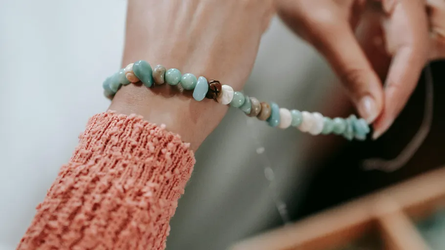 Hand trägt ein buntes Perlenarmband.