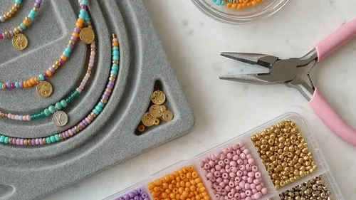 Beaded necklaces, pliers, and beads on a table.