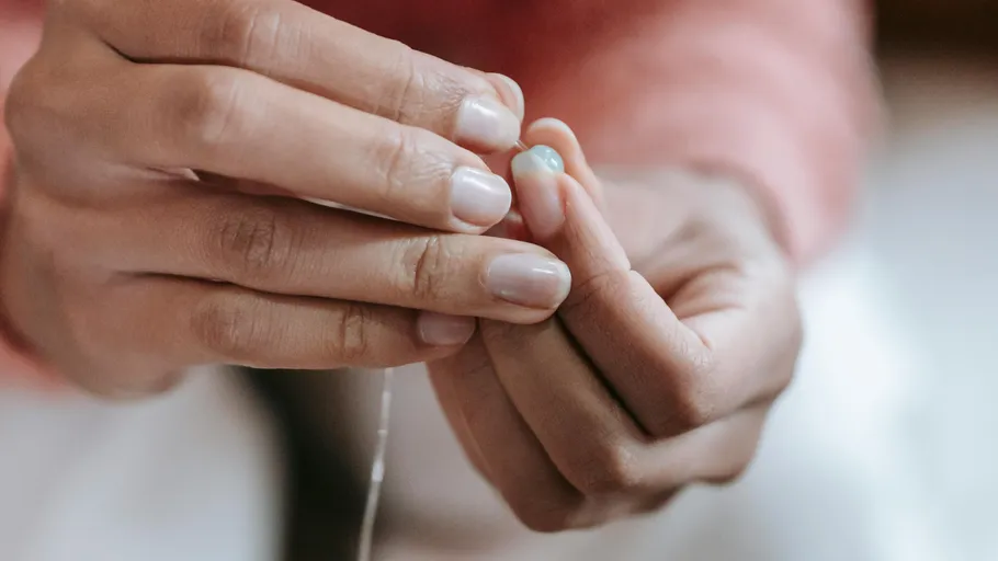 Close-up of hands threading a small bead.