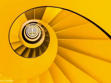 Gelbe Wendeltreppe, spiralförmig, führt nach oben zu Licht.