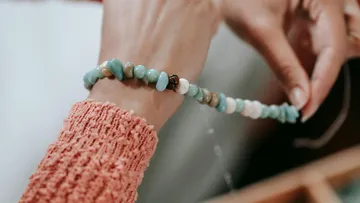 Person hält ein Perlenarmband in Händen.