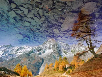 Snow-capped mountains are reflected in the calm water.