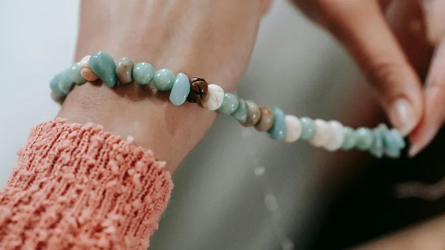 Perlenarmband wird von zwei Händen gehalten.