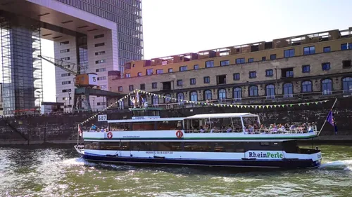 Boot segelt auf Fluss, Industriegebäude daneben.