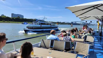 People on riverboat with bridge view.