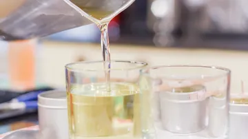Pouring wax into a glass candle mold.