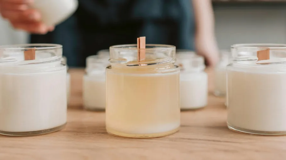 Candles with wooden wicks on wooden table.