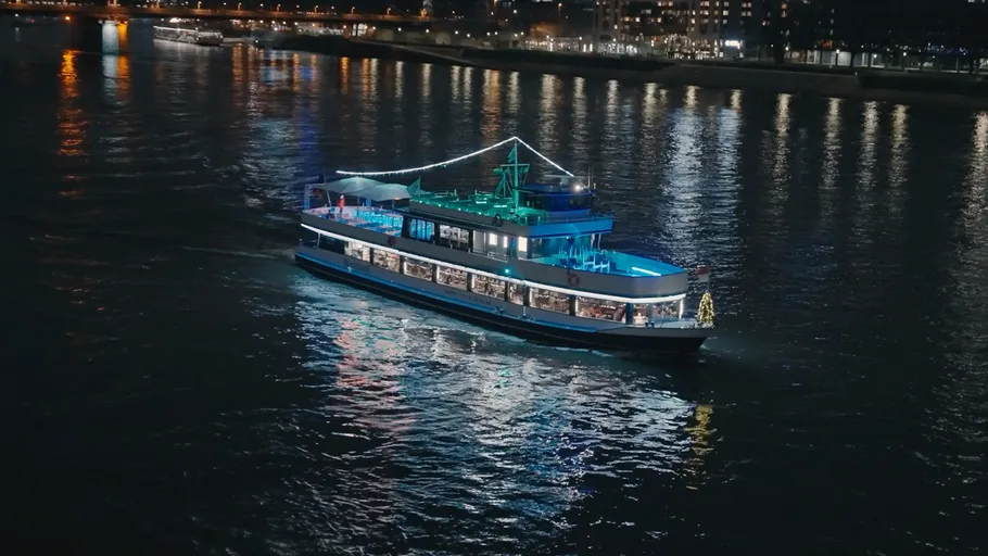 Illuminated boat cruising on river at night.