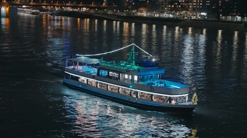 Illuminated boat cruises on nighttime river.