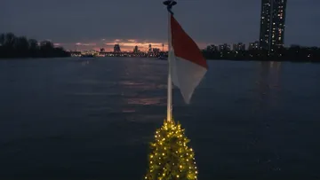 Flagge und Lichter auf Boot bei Sonnenuntergang.