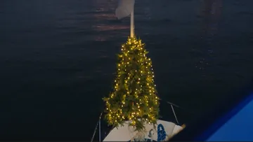 Beleuchteter Weihnachtsbaum auf Boot bei Nacht.