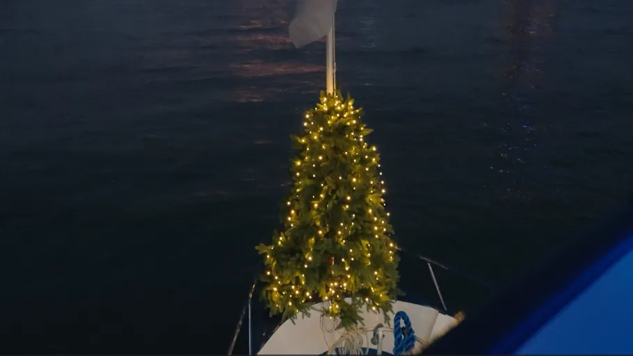 Beleuchteter Weihnachtsbaum auf Boot bei Nacht.