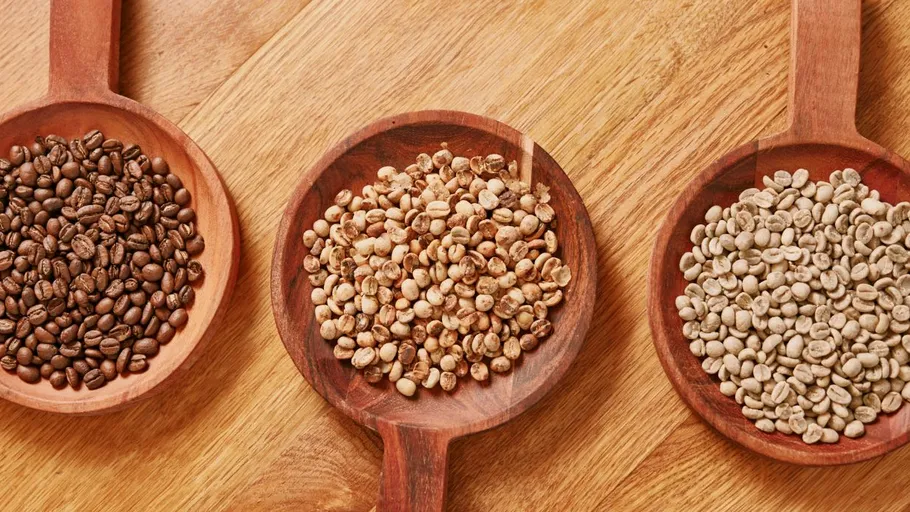 Three types of coffee beans on wooden scoops.