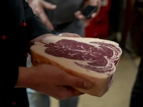 Pork piece in hands, presented in a busy environment.