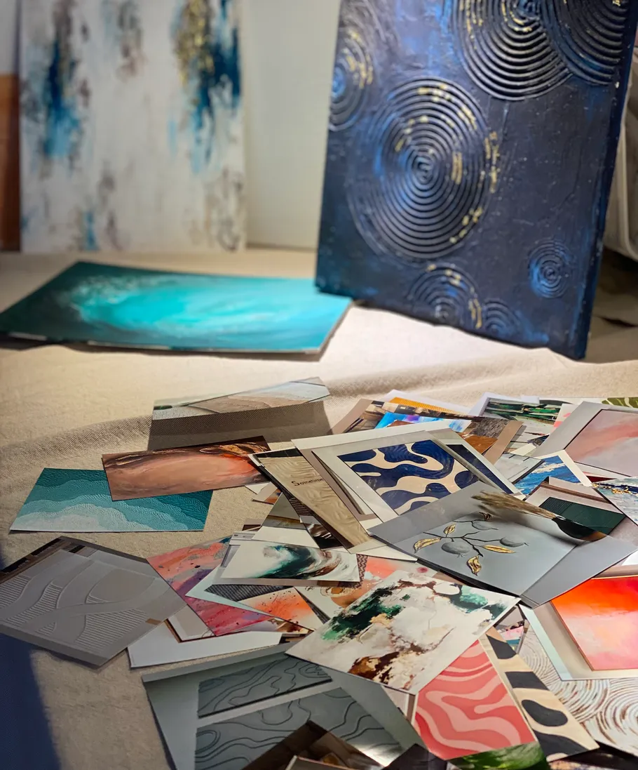 Art prints scattered on floor, paintings in background.