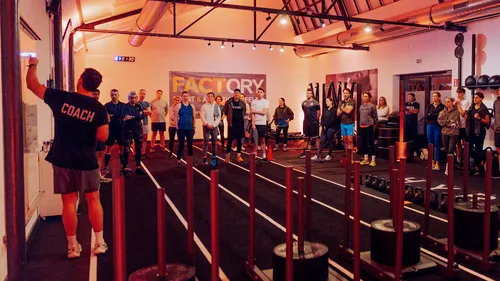 Trainer leitet Trainingsgruppe in Fitnessstudio.